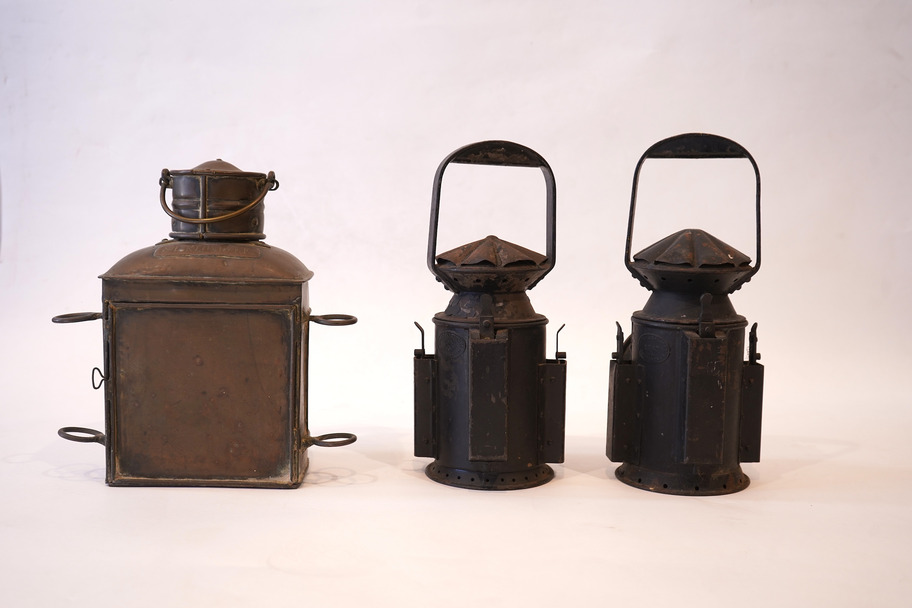 Two black painted railway hand lamps by Pratt & Co. Ltd. Birmingham, both dated 1945, both with burners and reflections, one intended for three colour aspect, with one glass missing, together with a brass ship’s bulkhead